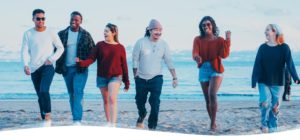 group of happy multiethnic young adults walking on the beach