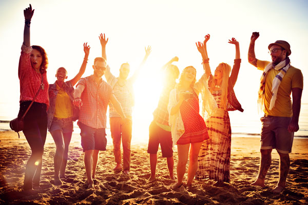 group of happy people dancing in the beach