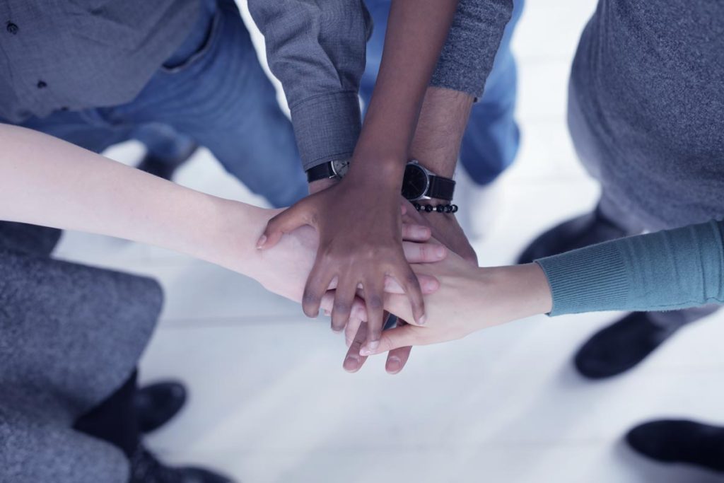 a group of people, multicultural group stacking hands together